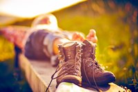 Wanderer der sich gerade auf einer Bank ausruht, im Fokus seine Wanderstiefel