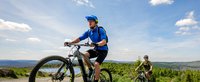Zwei Mountainbiker fahren einen Berg hinauf bei sonnigem Wetter
