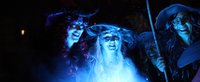 Hexen schauen über beleuchteten Kessel in die Kamera