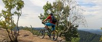 Mountainbiker steht auf einem Felsen und schaut in die Ferne